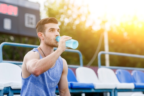 Man in summer sport shirt drinking sports energy drink.